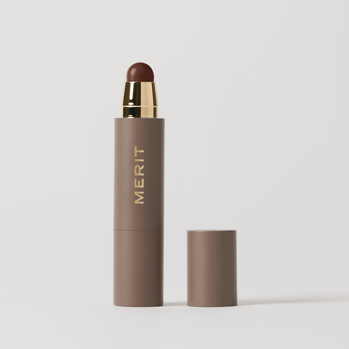 Master || A stick complexion product with MERIT written on it, with the cap removed, showing the product in shade Bistre.