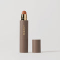 Master || A stick complexion product with MERIT written on it, with the cap removed, showing the product in shade Sienna.