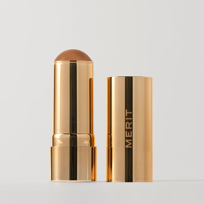 Master || A stick bronzer product by MERIT, with the cap off, showing the bronzing cream inside and MERIT on the cap.